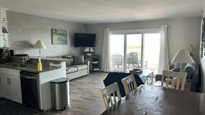 A modern kitchen with a dining area, a sofa, and a TV. - Relax Oceanfront at our 2-bedroom Oceanfront condo in Carolina Beach (Carolina Beach)
