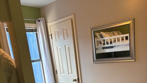 A room with a wooden dresser, a white door, and a window with curtains. - Relax Oceanfront at our 2-bedroom Oceanfront condo in Carolina Beach (Carolina Beach)
