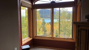 A room with a large bay window overlooking a lake and autumn foliage. - Beautiful cabin in aspen forest, amazing deck, lake and mountain views, private (Grand Lake)