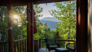 A wooden deck with wicker furniture, overlooking a forested area and a mountain. - Beautiful cabin in aspen forest, amazing deck, lake and mountain views, private (Grand Lake)