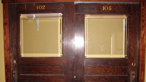 A wooden double door with two glass panels, each marked with a number (102 and 105). - The Nest: Beautiful Apartment Style Lodging In The Heart Of Downtown Decorah. (Decorah)