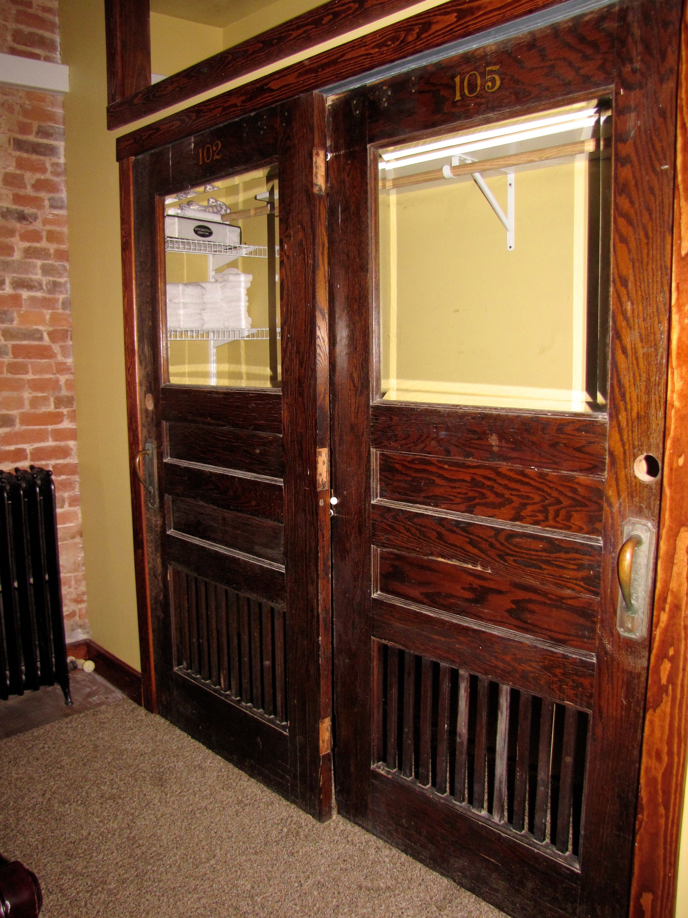 A wooden double door with a glass panel, numbered 102 and 105, and a radiator to the left.