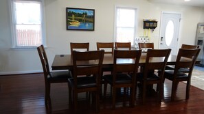 A dining room with a wooden table and chairs, a painting on the wall, and a door with a small shelf above it. - Firepit, Beach, Pier and Gorgeous views without leaving your home ! ! ! (Pasadena)