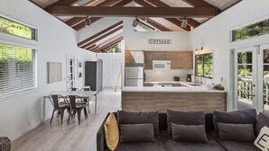 Eine moderne Küche mit einem 'COTTAGE'-Schild, Holzbalken und einem Essbereich mit einer Couch und Stühlen.
