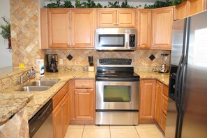 A kitchen with wooden cabinets, a stainless steel microwave, oven, and refrigerator.