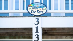 Een huis met een balkon en een bord met daarop 'The Kure 313'.