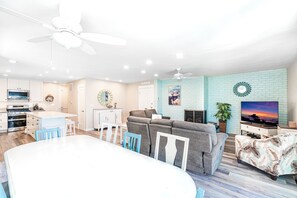 Relax in this stylish living space with a dining area, sofa, and TV, surrounded by decorative wall art and a brick-patterned wall.