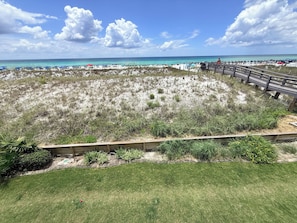 Ein Strand mit Holzzaun, Rasenflächen und freiem Blick auf das Meer.