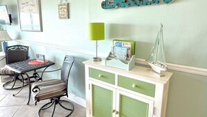 A room with a green wall, a desk, a chair, a cabinet, and a decorative sign that reads "Beach".