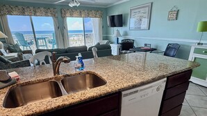 A kitchen with granite countertops, a double sink, and a dishwasher.
