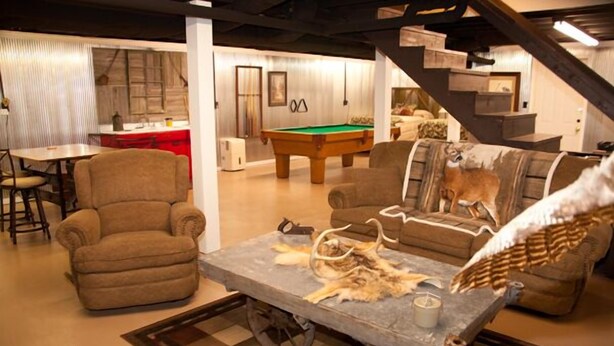 Un salon chaleureux avec une table de billard, des sièges confortables et un escalier.