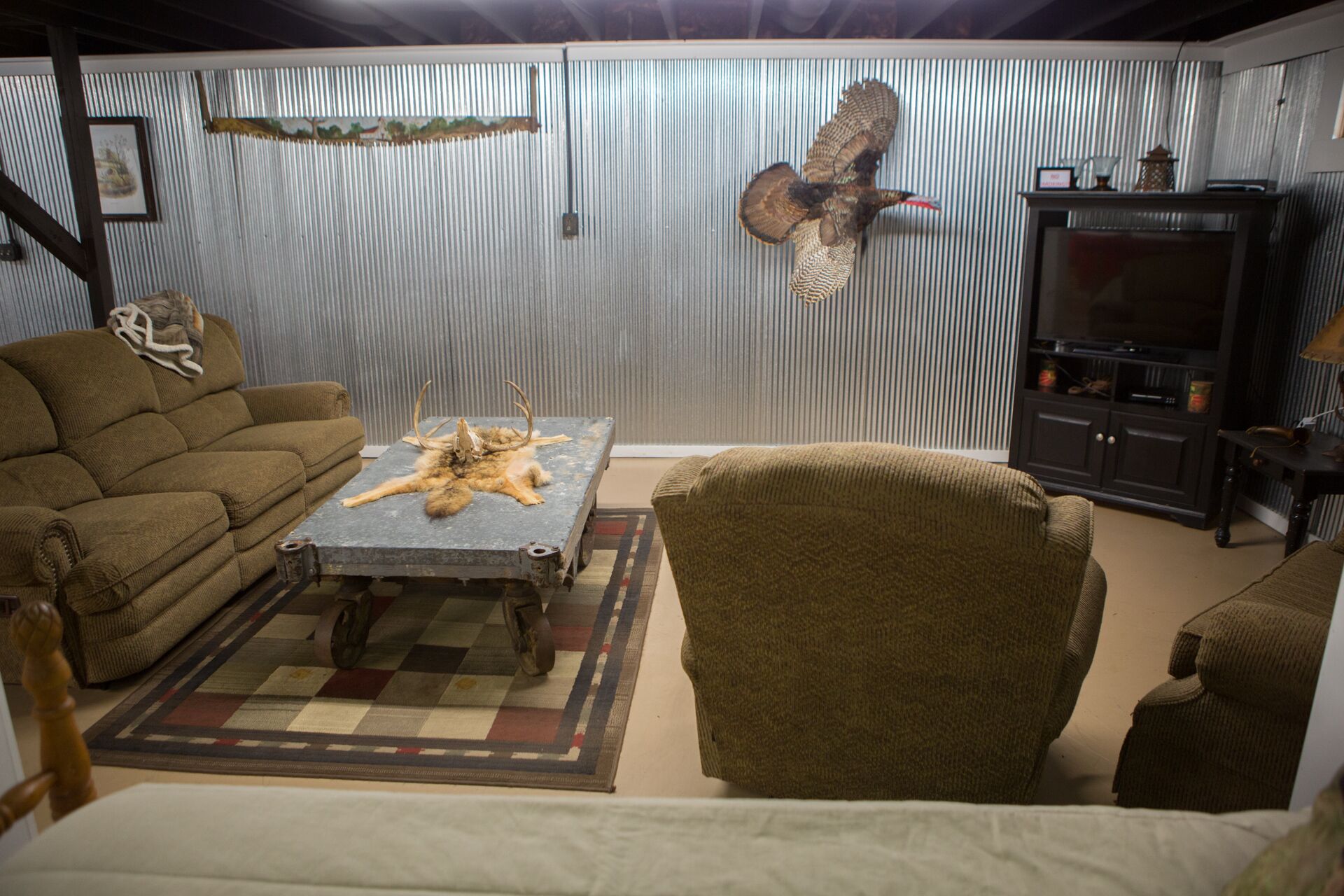 Ein Zimmer mit einer Couch, einem Sessel und einem Tisch mit einem Fellteppich.