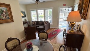 Un coin repas avec une table ronde, des chaises, un vase de fleurs et un ventilateur de plafond.
