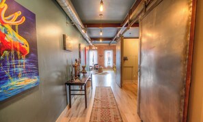 A hallway with a wooden floor, a rug, and a colorful painting on the wall. - Your Nest Away From Home (Missoula)