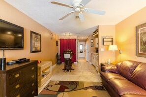 A hotel room with a TV, a ceiling fan, a dining area with a red curtain, a sofa, and a lamp. - Beach Lovers , and Divers Paradise, with a great Night life..... (Navarre)