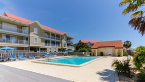 Et hotel med swimmingpool, flere balkoner og en træterrasse.