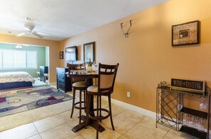 A room with a dining table, chairs, a wine tasting cart, a bed, and a ceiling fan. - Beach Lovers , and Divers Paradise, with a great Night life..... (Navarre)