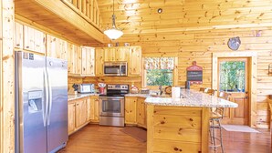 Cocina de cabaña de madera con refrigerador, microondas y horno de acero inoxidable.