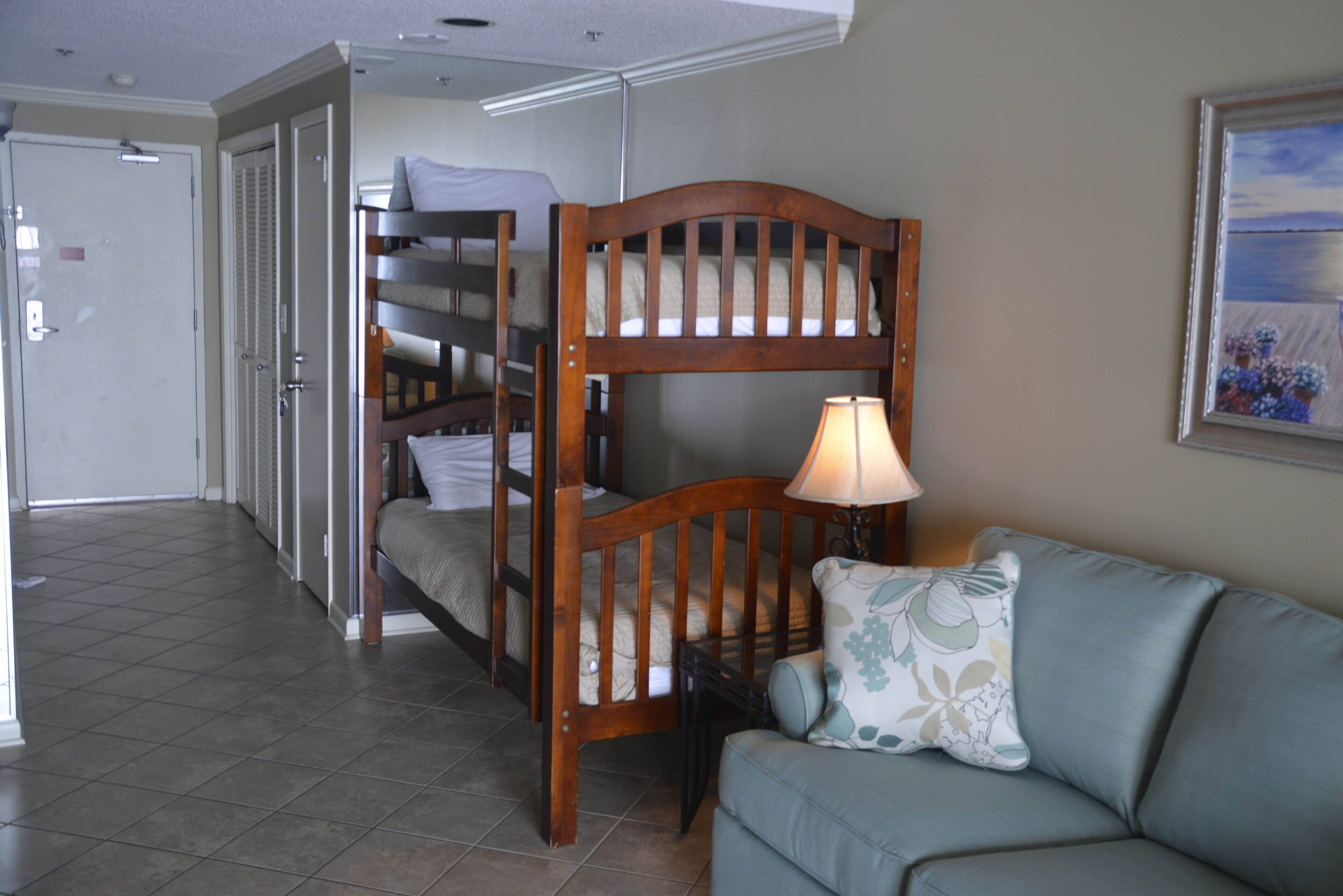 A room with bunk beds, a sofa, and a lamp.