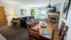 Una sala de estar acogedora con chimenea, una mesa de comedor con sillas, un sofá y un televisor.