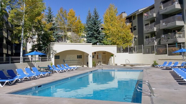 Ein Swimmingpool mit blauen Liegestühlen und ein Gebäude mit Rundbogenportalen.