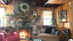 A cozy cabin interior with a stone fireplace, wooden walls, and a leather sofa. - First-Tier Lakefront Log Charmer! Lakeview Spa In Gazebo,Fireplace,Deck,Sledding (Big Bear Lake)