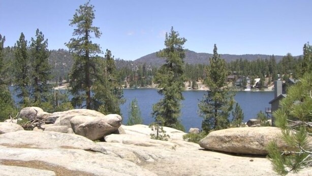 A rocky shoreline with a lake and trees in the background. - First-Tier Lakefront Log Charmer! Lakeview Spa In Gazebo,Fireplace,Deck,Sledding (Big Bear Lake)