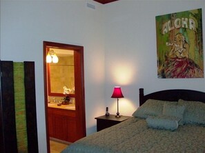 Relax in this inviting bedroom with a large bed, nightstand, and bathroom access.
