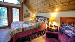 A bedroom with a wooden ceiling, a large bed with a quilt, two bedside lamps, a clock, and a window with blinds. - Mystic Views (Yosemite National Park)