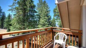 A wooden deck with a white plastic chair, overlooking a forested area. - Mystic Views (Yosemite National Park)