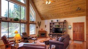A spacious living room with a fireplace, a television, and a wooden ceiling. - Mystic Views (Yosemite National Park)