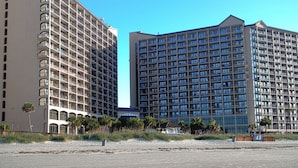 Un hotel con diversi piani, balconi e vista sulla spiaggia.