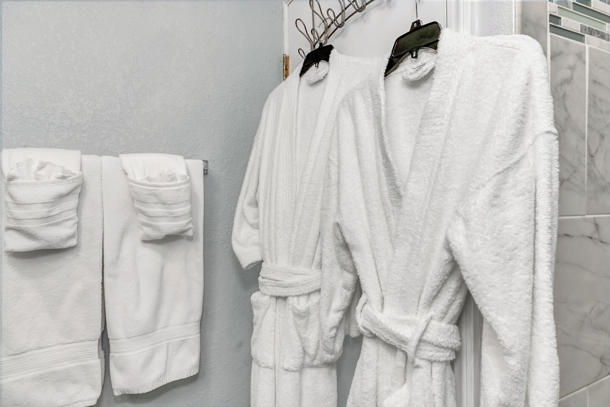 Un bagno con asciugamani e accappatoi bianchi appesi a un portasciugamani.