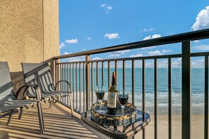 Un balcon avec une table dressée pour deux personnes, agrémentée d’une bouteille de vin et de deux verres.