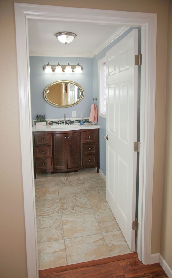 A bathroom with a vanity, mirror, and light fixture. - Seafarer's Beach House Beach Front Property, Amazing Views! (Homer)