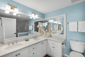 A bathroom with a double sink vanity, a large mirror, and a toilet.
