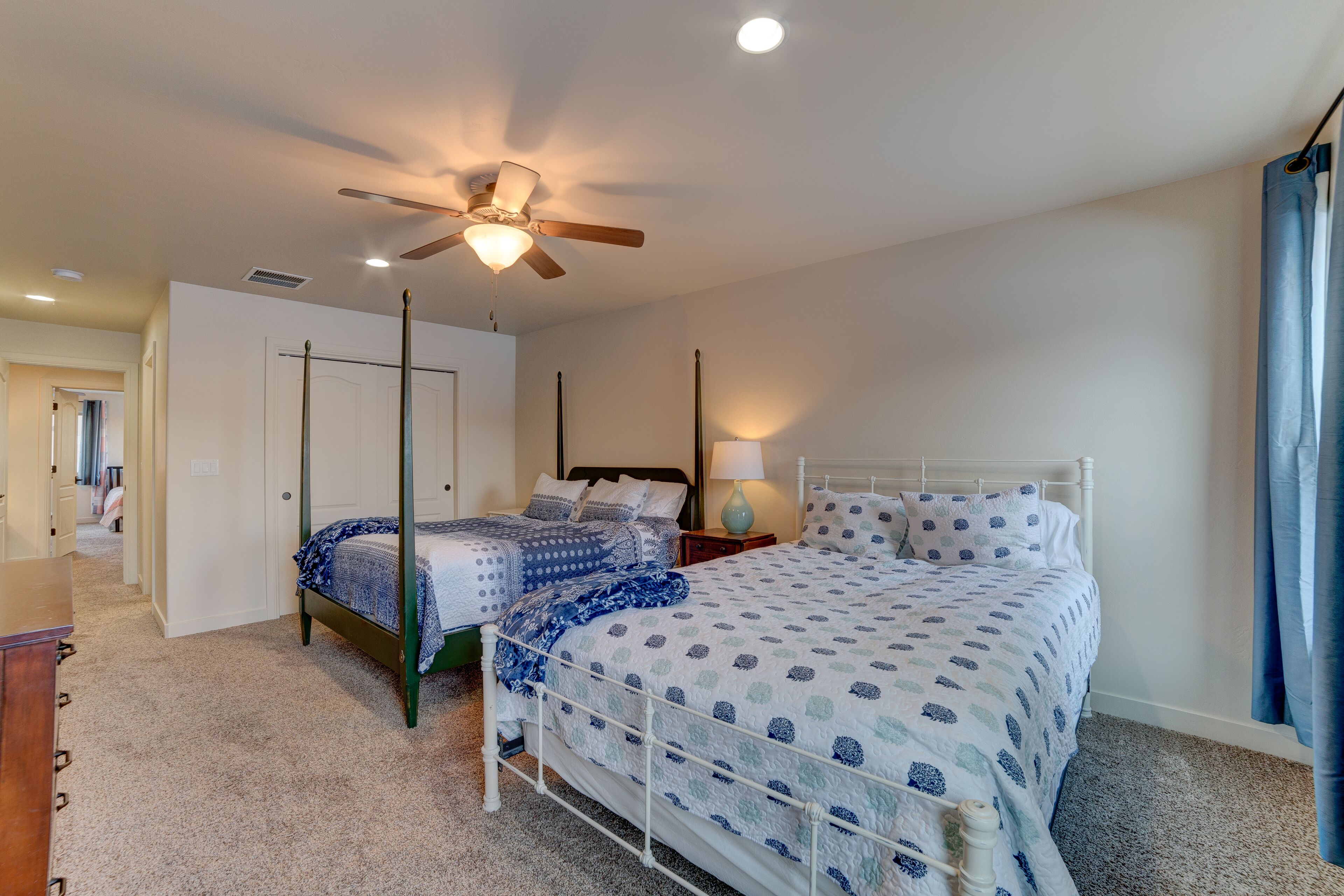 A bedroom with two beds, a ceiling fan, a nightstand, and a lamp.