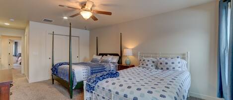 A bedroom with two beds, a ceiling fan, a nightstand, and a lamp.
