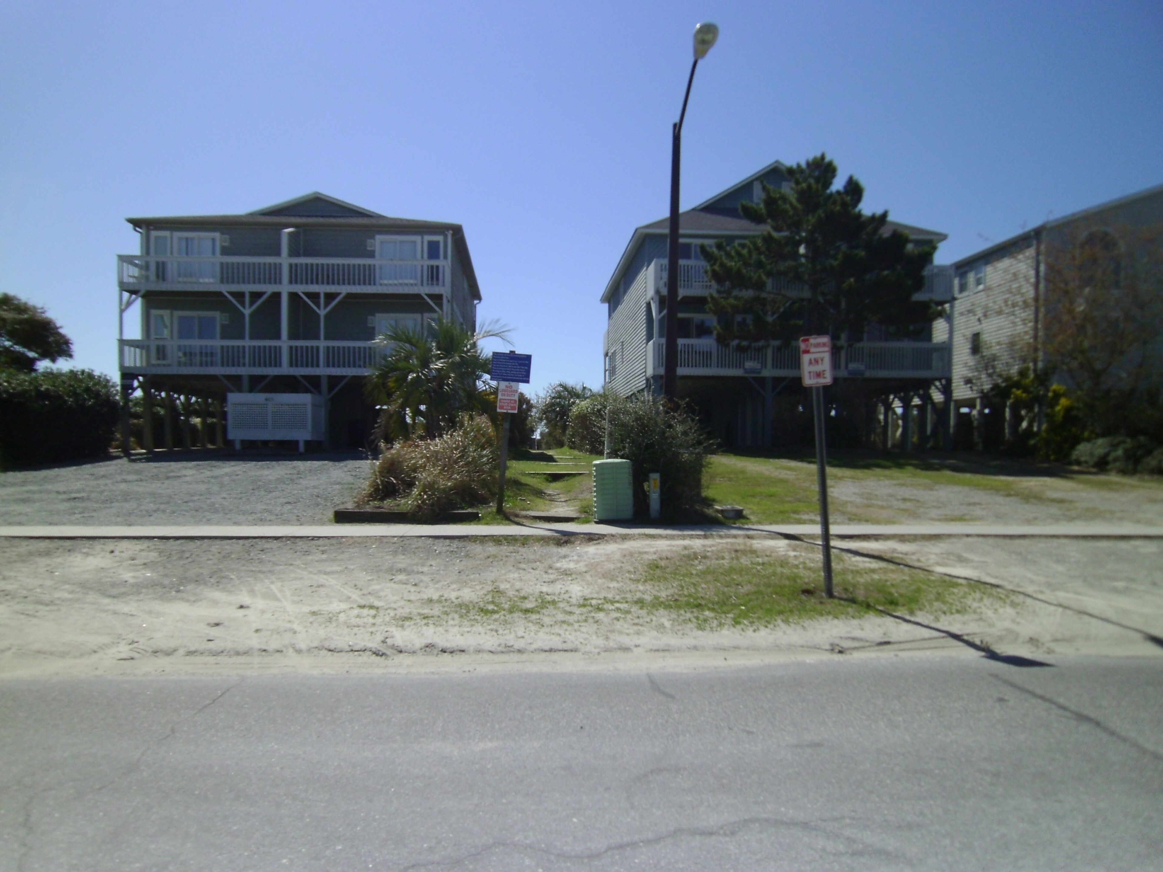 A two-story building with a balcony, a street lamp, and a sign indicating no parking at any time.