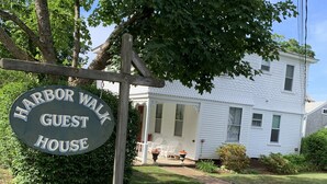 A sign for Harbor Walk Guest House with a white house in the background. - Walk from your family friendly house to the beach, downtown, or Wychmere Resort (Harwich Port)