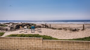 Ein Strand mit einigen Stühlen und einer Bank, ein sandiger Weg und Blick aufs Meer.