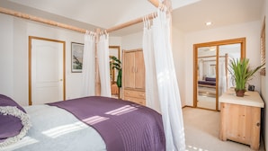 Ein Schlafzimmer mit einem Himmelbett, einem Holzschrank und einem Nachttisch mit einer Pflanze.