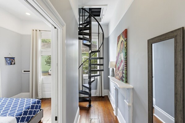 A bedroom with a bed, a staircase, and a painting on the wall.