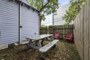 A backyard with a picnic table and chairs, a wooden fence, and a shed.