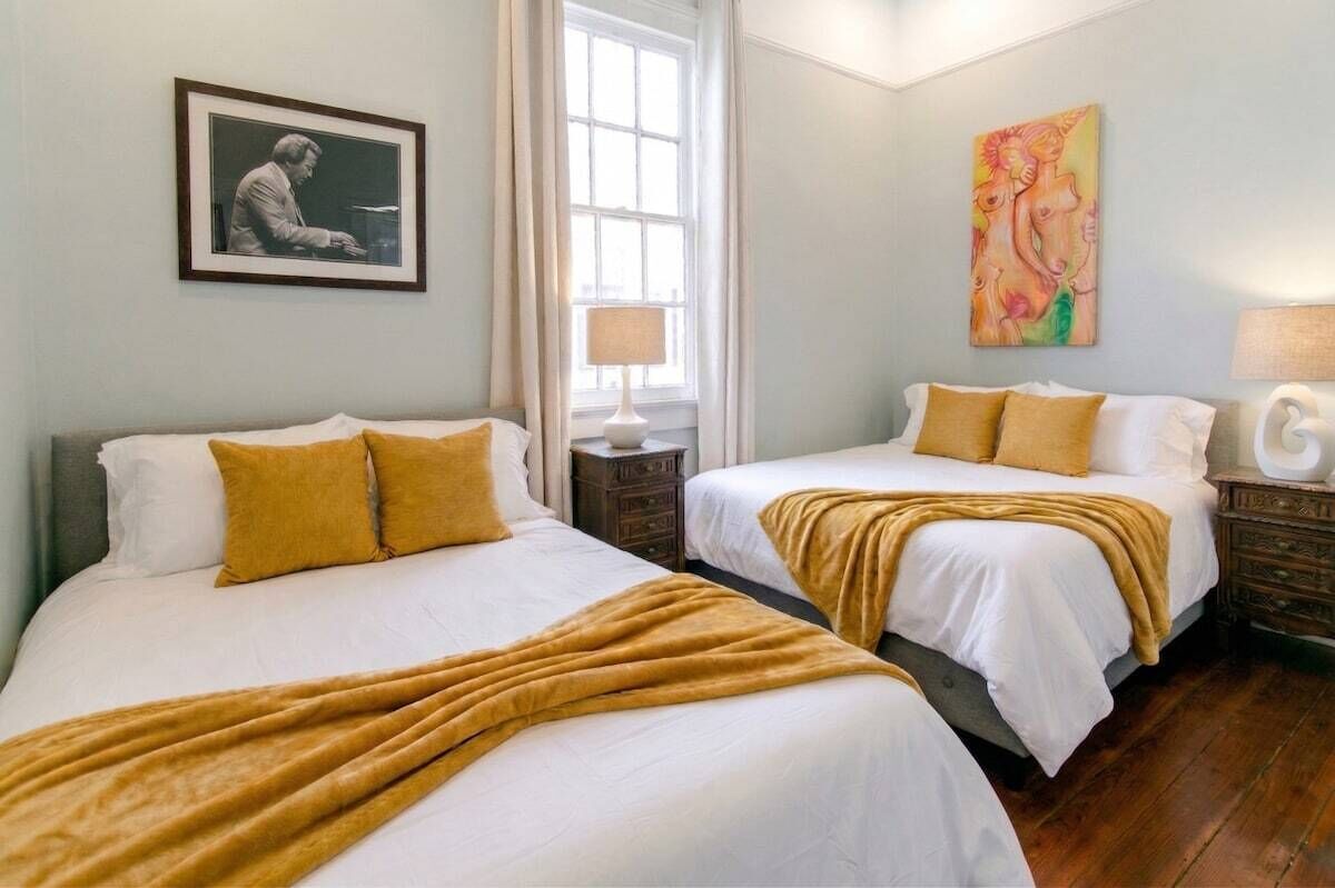 Een hotelkamer met twee bedden, een raam, een schilderij en een lamp.