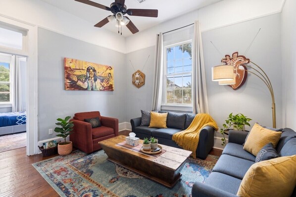 A living room with a sofa, armchair, coffee table, and a painting on the wall.