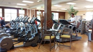 Une salle de sport équipée de plusieurs tapis de course, de vélos d’exercice et de poids libres.