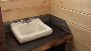 Un baño con paredes de madera, un lavabo blanco y una encimera oscura.