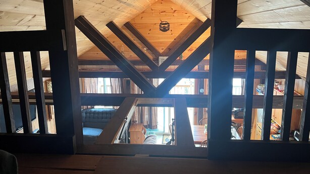 Una habitación con techos altos, vigas de madera a la vista y techo inclinado.