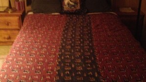 Un dormitorio con cama, una ventana con cortinas, una lámpara y una luz de aro fijada a la pared.